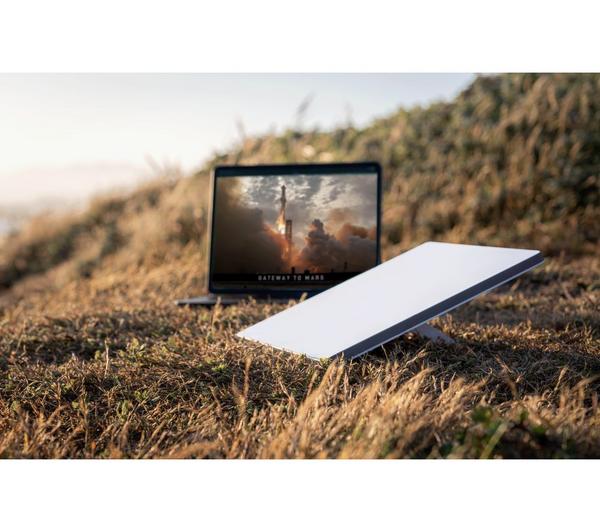 Starlink Mini dish set up in a field next to a laptop